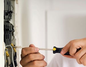 Electrician wiring a wall socket with a screwdriver